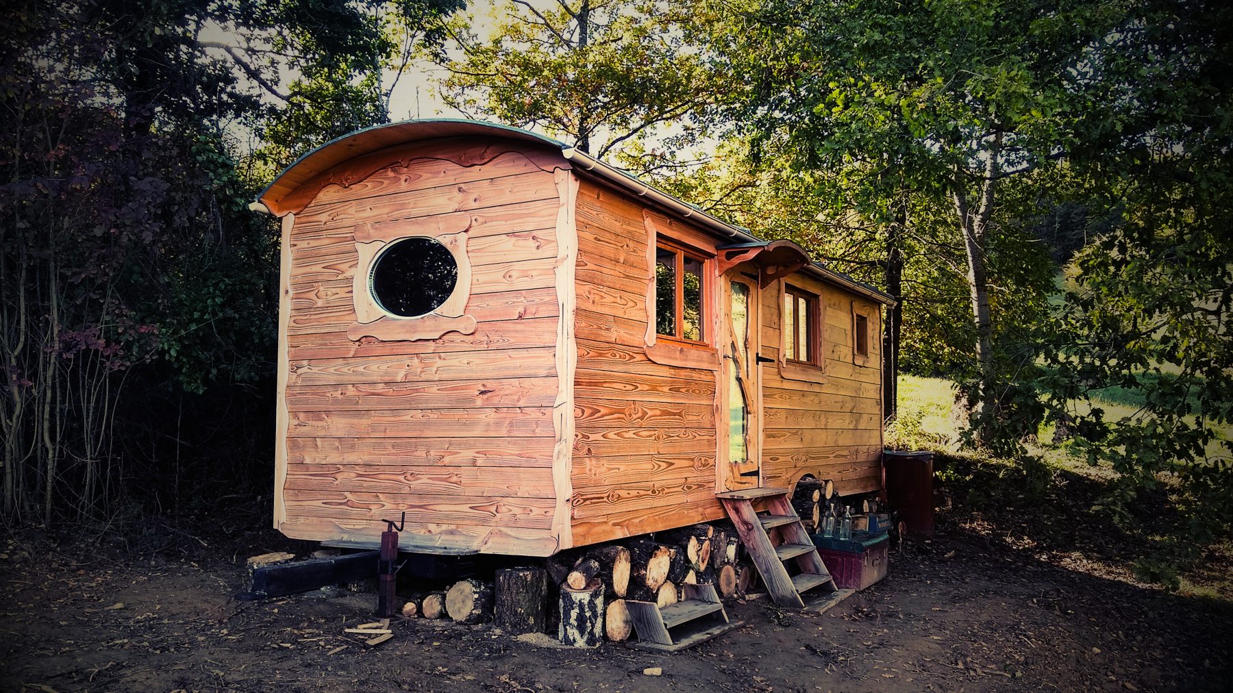 Roulotte en bois avec hublot rond et bois de chauffage empilé